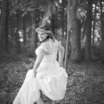 Lächelnde Braut im Wald, in einem fließenden Kleid und Blumenkranz, Schwarz-Weiß-Fotografie